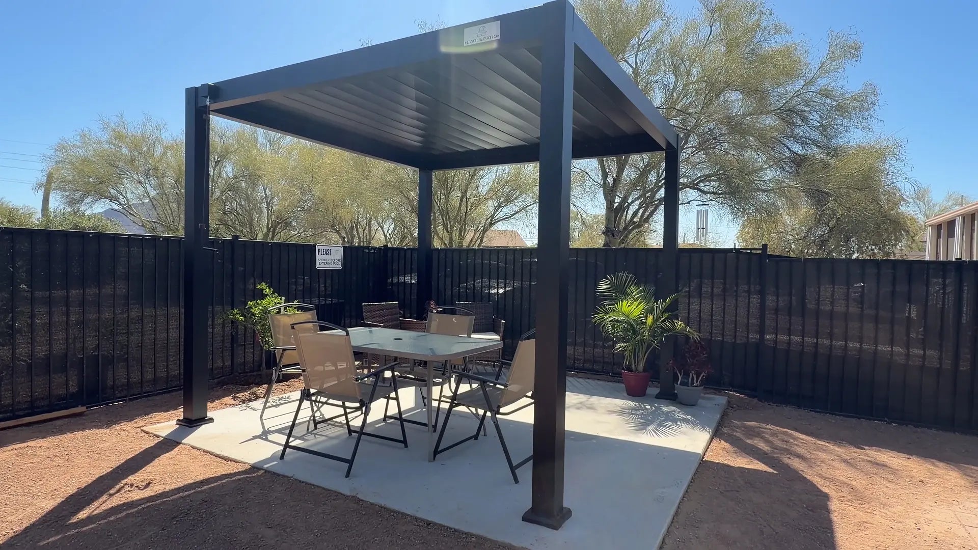 Aluminum louvered pergola installed on a backyard patio with visible post bases and patio surface support area.