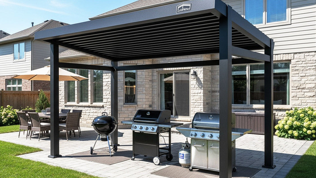 An elegant black metal louvered pergola covers a patio with three grills (a kettle grill and two gas grills) against a stone-veneer house. Outdoor dining furniture and greenery are visible nearby.