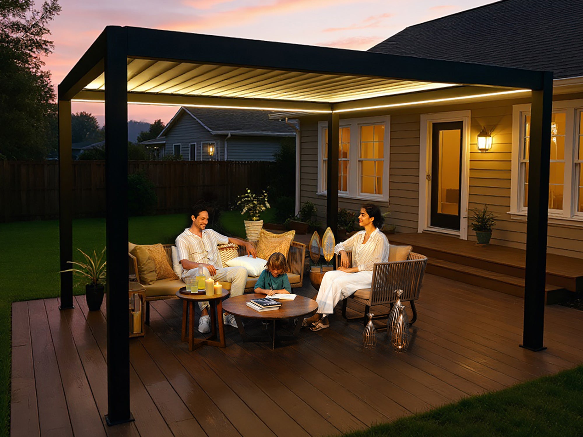 Black aluminum louvered pergola with integrated lighting - family relaxing on wooden deck with outdoor furniture.